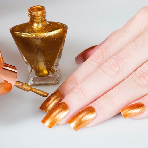 Woman applying golden nail polish